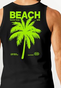 Schwarzes Tanktop mit einem großen grünen Palmbaum-Graphic und dem Text "BEACH Social Club 1976" sowie "LONG BEACH SURF VACATION" und Logo.