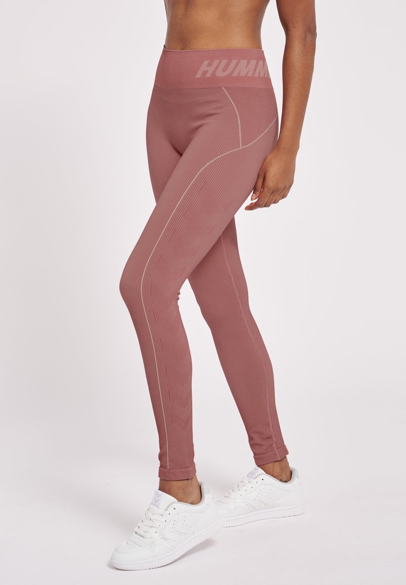 Legginsy fitness w miękkim odcieniu różu, z prążkowaną fakturą, wysokim stanem z logo "HUMM" oraz wzorem w zygzak z boku.