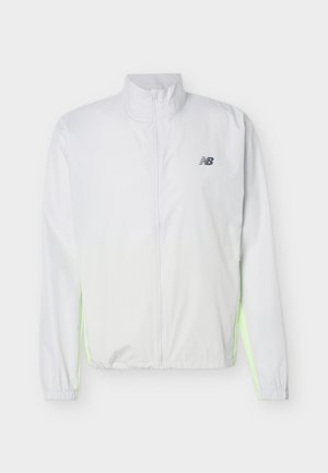 Veste blanche légère avec fermeture éclair intégrale à l'avant, poignets élastiques, panneaux latéraux néon, et petit logo New Balance noir sur la poitrine.