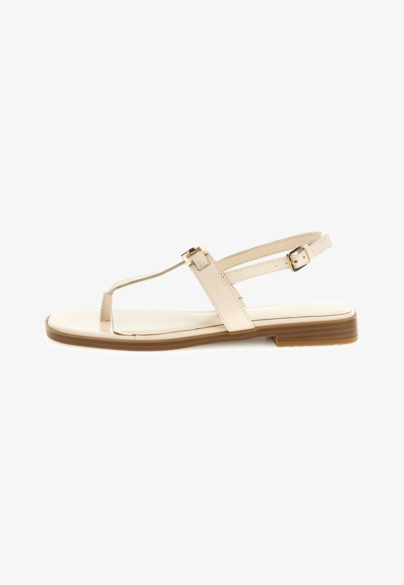 Nude synthetic sandal with a flat sole, T-strap design, and adjustable ankle strap featuring a gold-tone buckle accent.