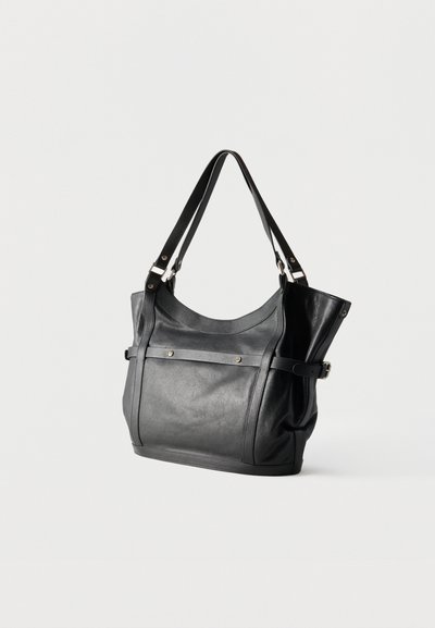 Μαύρη δερμάτινη τσάντα ώμου με δύο λουράκια, μπροστινή τσέπη ασφαλισμένη με δύο πριτσίνια και λεπτομέρεια με πόρπη στο πλευρό, σε λευκό φόντο.