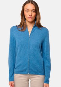 Sweat à zip bleu fabriqué à partir d'un matériau doux et texturé. Il dispose d'un col montant et de manches longues. Design uni sans motifs ni accents supplémentaires.