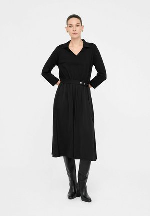 Abito nero con maniche lunghe, colletto a V, vita cintata e gonna plissettata. Tessuto liscio, design minimalista, con due bottoni sulla cinta.