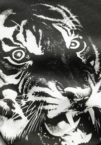 Tela negra con una ilustración de la cara de un tigre blanco audaz, con ojos detallados, bigotes y patrones de piel texturizados.