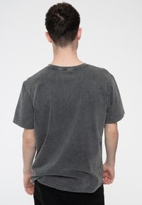 Gray cotton T-shirt with a soft texture, short sleeves, and a round neckline. The fabric has a faded, worn look.