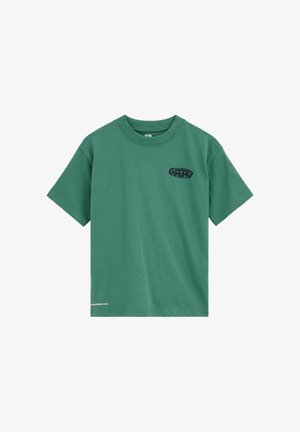 Groen T-shirt met korte mouwen en ronde hals, met een zwart "ARGHD"-logo op de linkerborst en kleine witte tekst vlak bij de onderzoom.