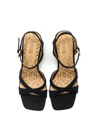 Sandali in suede neri con un ampio design a fascia incrociata, punta quadrata, cinturino alla caviglia regolabile e una soletta beige texture con motivi di foglie.