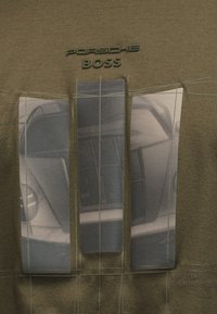 Απαλό τεχνικό σχέδιο του μπροστινού μέρους ενός αυτοκινήτου Porsche χωρισμένο σε τρεις κάθετες επιφάνειες με το κείμενο "PORSCHE BOSS" πάνω σε καφέ ύφασμα.