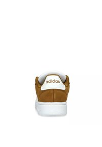 Zapatillas de gamuza color arena con suela de goma blanca, que presentan un cuello acolchado y un logotipo "adidas" en relieve en la parte trasera en dorado.