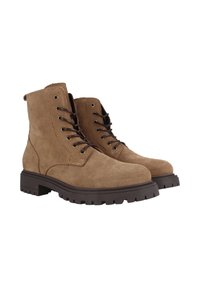 Botas de ante marrón hasta el tobillo con punteras redondas, cordones en la parte delantera y suelas de goma con tacos. Cuenta con ojales de metal y detalles de costura reforzada.