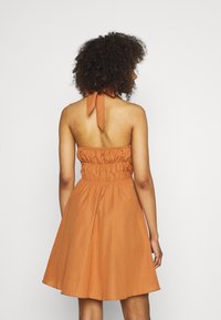 Krátké oranžové šaty s přiléhavým živůtkem a na zádech sbíraným detailem. Mají zavazování kolem krku a rozšířenou sukni, vyrobené z lehké látky.