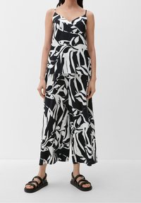 Ensemble deux pièces noir et blanc avec un haut sans manches à couches et un pantalon à jambes larges. Le tissu présente un motif texturé plissé.