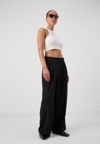 White cropped tank top, high-waisted black wide-leg trousers, black shoes, purple-accented sunglasses, smooth fabric, sleek design.