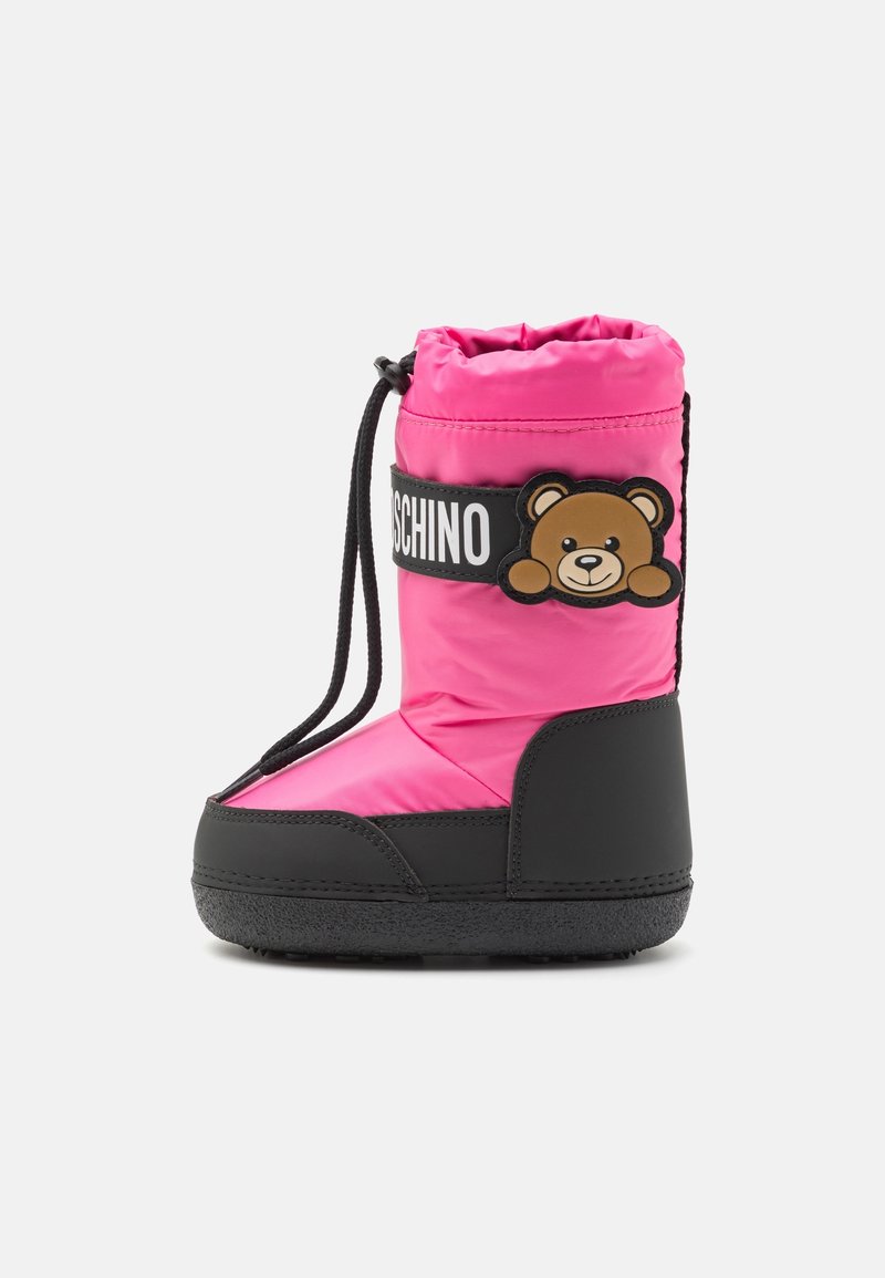 Botte d'hiver rose pour enfant avec semelle noire et cordon de serrage, ornée d'une sangle noire portant un visage d'ourson et le texte blanc "MOSCHINO".