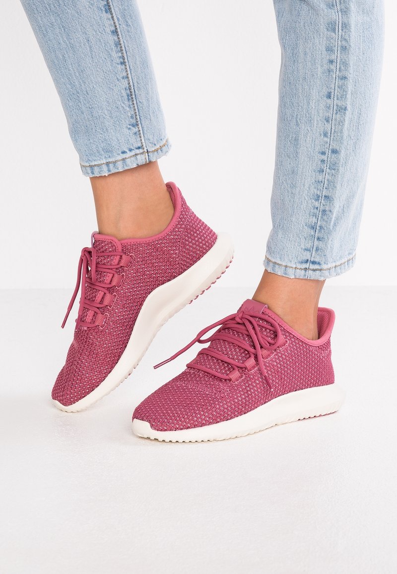 Rosa nät-sneakers med en texturerad överdel, platta snören och en vit gummisula. Designen har en rundad tå och minimal märkning.