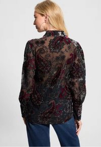 Blusa nera trasparente con motivo paisley bordeaux e argento, maniche lunghe a sbuffo e colletto. Tessuto testurizzato con un design fluido.