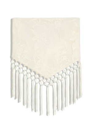 Châle couleur crème avec motif en dentelle florale et franges nouées le long du bord pointu sur fond blanc.