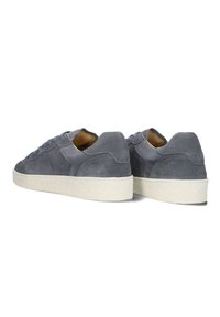 Grijze suède sneakers met een witte gestructureerde zool, voorzien van blauwe veters en een minimalistisch ontwerp. De achteraanzicht benadrukt het zachte materiaal en de stiksels.