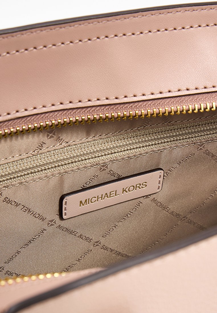 Michael Kors Tasche Innenraum; weiches rosafarbenes Leder mit einem goldenen Reißverschluss. Innenfutter aus beigem Stoff mit einem Logomuster und einem genähten Etikett.