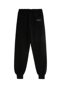 Pantalones de chándal negros con una cinturilla elástica, puños ajustados y dos bolsillos traseros con cierres a presión. Textura suave con un detalle mínimo.