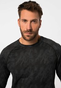 Schwarzes, langärmliges Sportshirt mit einem subtilen Muster, Rundhalsausschnitt und Logodetail auf der Brust. Weicher, elastischer Stoff.