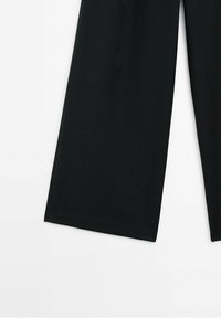 Pantalon noir à jambes larges, montré de la moitié de la cuisse jusqu'en bas, présenté sur fond blanc.