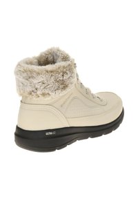 Botas de tobillo beige con cuello de pelo sintético, diseño perforado y suela negra acolchada etiquetada "ULTRA GO". Cordones y ojales de metal visibles.