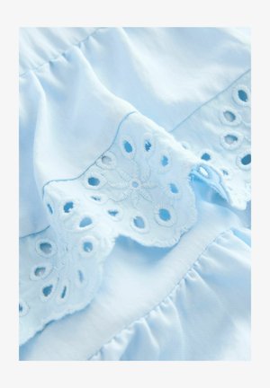 Hellblauer Baumwollstoff mit bestickten, gewellten Kanten und runden Ausschnitten sowie einem geschichteten Rüschendesign. Glatte Textur.