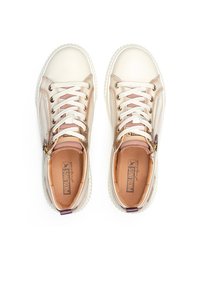 Zapatillas de color beige claro con un acabado suave y brillante. Cuentan con cordones blancos, cremalleras laterales y una suela texturizada. Detalle interior en cuero marrón.