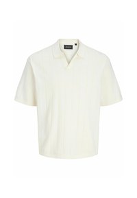 Polo en maille crème à manches courtes avec un subtil côtelé vertical et un petit col, étiquette « Aprel » à l'intérieur de l'encolure.