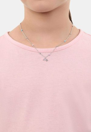 Collar de cadena de plata con cuentas de colores, que presenta un pequeño charm de arcoíris y estrella. Llevado sobre una camiseta rosa clara.