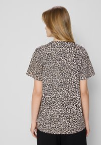 T-shirt met luipaardprint in lichtbeige met zwarte en bruine vlekken; korte mouwen, ronde halslijn en een relaxte pasvorm. Zachte stoftextuur.