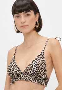 Μπικίνι τοπ από λεοπάρ σχέδιο με τριγωνικά cups, ρυπασμένο κάτω μέρος, ρυθμιζόμενους ιμάντες και χρώματα μαύρο και μπεζ.
