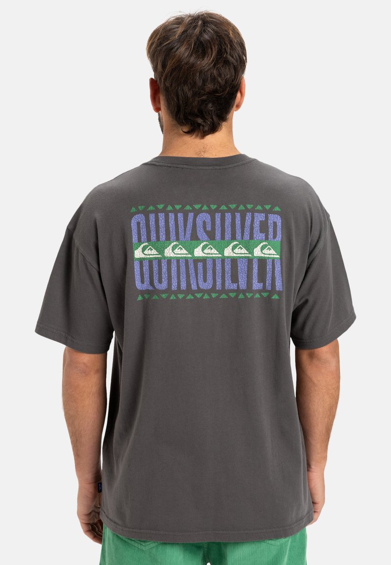 Grijze katoenen t-shirt met een groot blauw en groen "Quiksilver" logo en golfgrafieken, evenals driehoekpatronen op de achterkant.