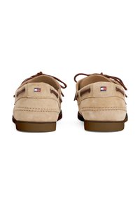 Beige suede boat shoes with brown laces, smooth texture, rubber sole, and a small colored logo on the back. Double eyelets for laces.