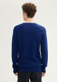 Blauwe gebreide trui met een getextureerd patroon, ronde hals, lange mouwen en ribgebreide manchetten en zoom. Zichtbare stiksels.
