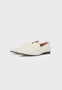 Valkoiset loafers, jotka on valmistettu sileästä synteettisestä materiaalista. Ominaisuuksiin kuuluu ristikkäinauhoitus ja matala ruskea kanta. Puhtaat, minimalistiset linjat.