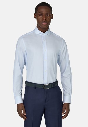 Camisa de vestir a rayas en azul claro con cuello puntiagudo, mangas largas y botones, combinada con pantalones oscuros azules y un cinturón negro.
