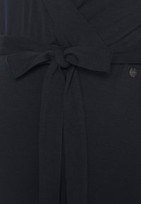 Vestido preto envelopado com um cinto amarrado na cintura, textura de tecido suave e um pequeno detalhe de logotipo perto da cintura. Acabamento liso, sem padrões.