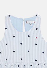 Světle modré šaty s bílými pruhy, námořnickými srdíčky a nabíranou sukní. Mají zapínání vzadu a logo v červené, bílé a modré barvě.