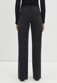 Black wide-leg jeans with a high waist and five-pocket design. Fabric appears smooth with a slightly faded finish and minimal stitching details.
