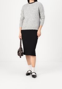 Harmaa neulepusero, jossa pyöreä pääntie, musta kapea hame, valkoiset röyhelöiset sukat ja mustat kengät koristenauloilla. Ruskea käsilaukku.