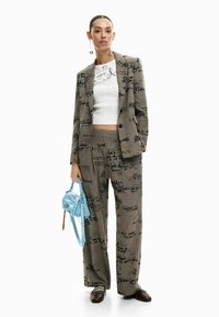 Hall triiksärg halli ruudustikuga, millel on musta käsitsi kirjutatud tekst, kombineeritud valge lühikese toppi ja helesinise käekotiga. Komplekti kuuluvad laiad püksid ja pruunid kingad.