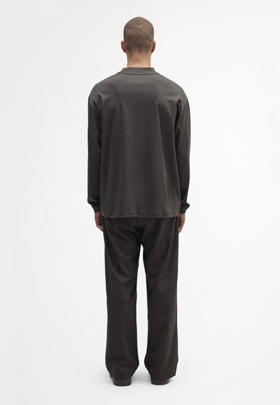 Lässiges, dunkelgraues Langarmoberteil mit rundem Hals, kombiniert mit weit geschnittenen, dunkelbraunen Hosen. Einfaches Design und weicher Stoff.