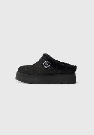 Zwarte klompen met een textuur bovenkant en een nep bont voering. Beschikt over een chunky platform en een hexagon hardware accent aan de zijkant.