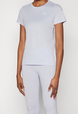 Persoon draagt lichtgrijze korte mouwen Puma t-shirt en bijpassende legging, staand met ontspannen armen langs het lichaam op een witte achtergrond.