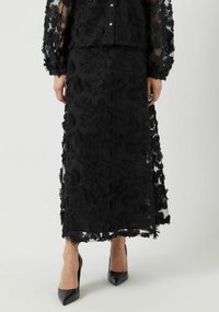 Svart brodert todelt sett med en gjennomsiktig topp med langermet og en matchende skjørt med blomsterutskrifter og frynse detaljer.