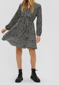 Černé šaty s květinovým vzorem, dlouhými rukávy, se zúženým pasem a rozšířenou sukní. V kombinaci s černými šněrovacími bojovými botami.