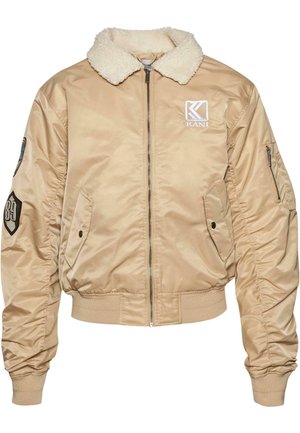 Beige bomber jacket with a faux fur collar, elastic cuffs, and waistband. Features a logo patch and side pockets for utility.