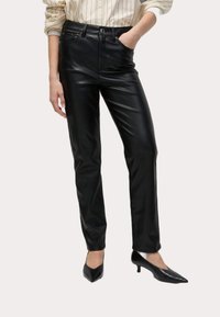 Svarta byxor i faux läder med smal passform, hög midja, fem fickor och en slät textur; matchat med svarta klackskor med spetsig tå.